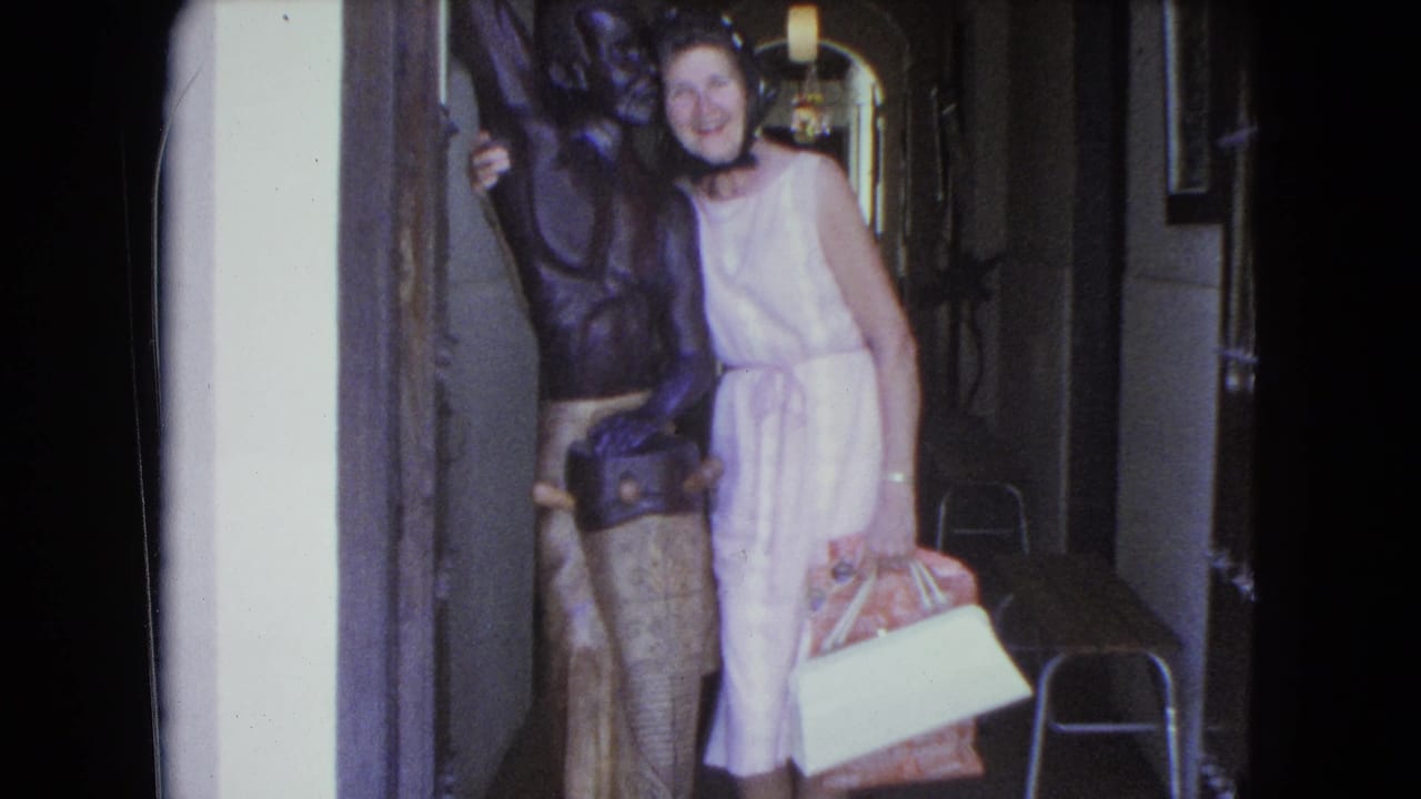 The woman remains posed next to the bronze statue in the San Juan corridor, with her pink dress and white shoes visible.