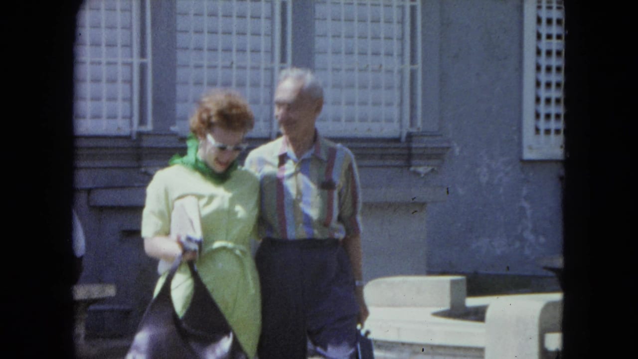 In 1964 San Juan, Puerto Rico, a woman in a lime-green dress and a man in a striped shirt walk together in bright sunlight.