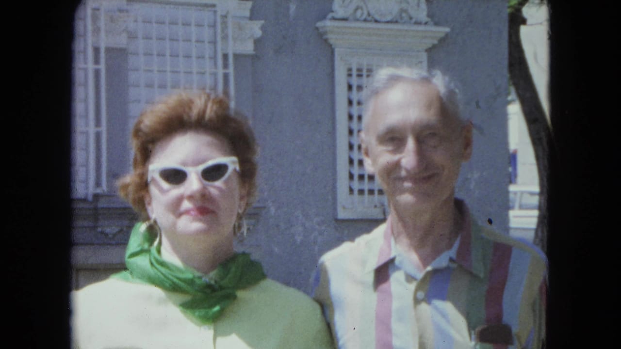 The woman in green and the man in a striped shirt face the camera outdoors in San Juan, Puerto Rico, in 1964 home-movie footage.