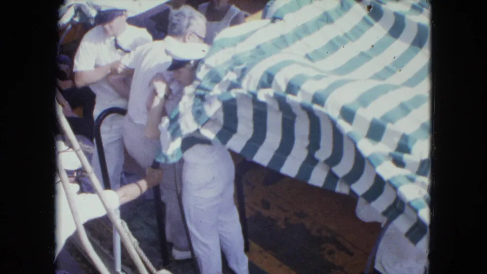 A small boat scene in San Juan shows a man standing as sailors work around a green and white canopy.
