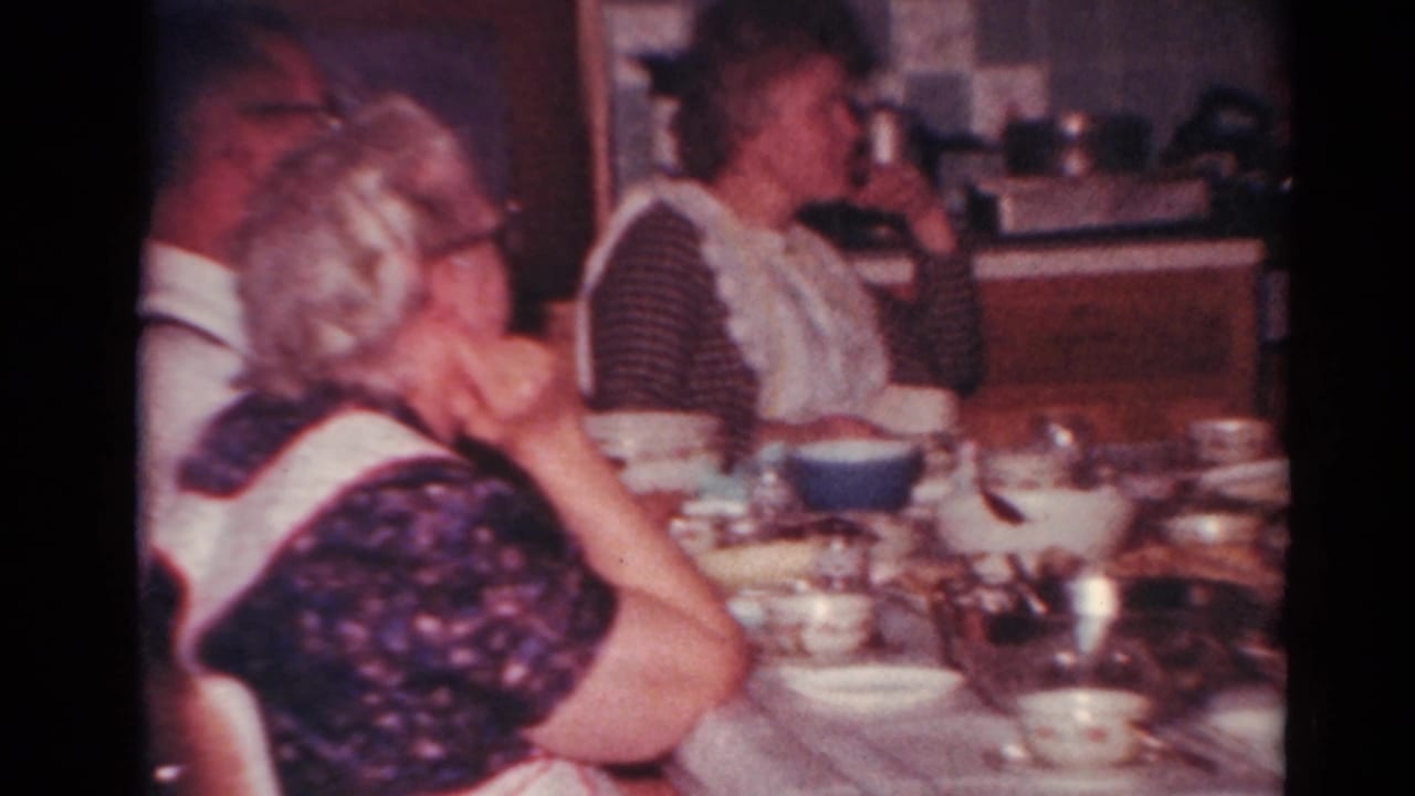 Adults seated at a crowded kitchen table during a family meal.