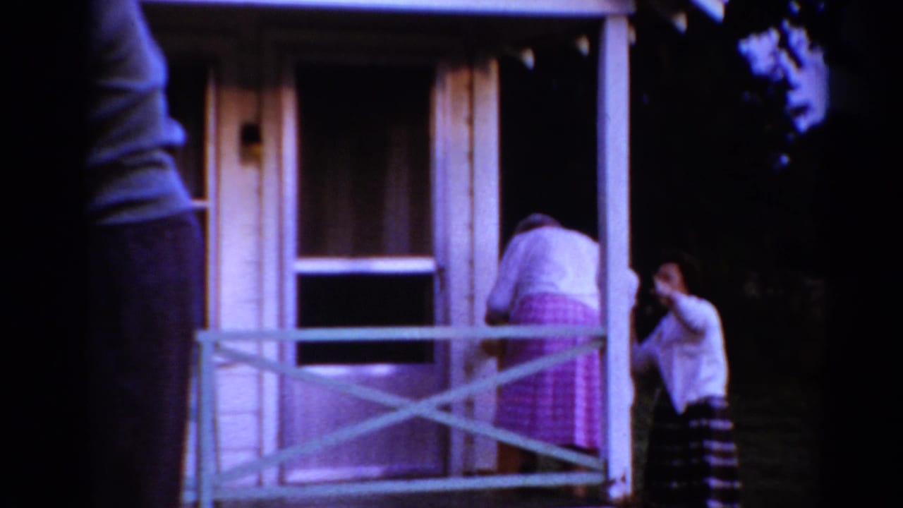 Older woman bends near the porch doorway while the younger woman stands at the side.