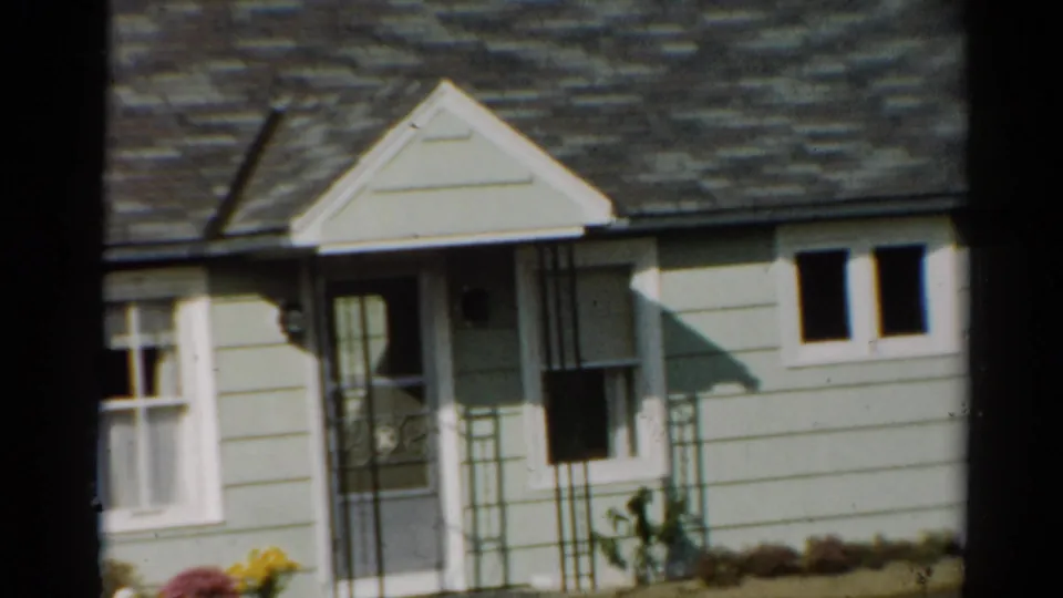 1964 Toledo frame showing the house facade shifted right, with porch railings, pale clapboard siding, roof shingles, and a small paired window.