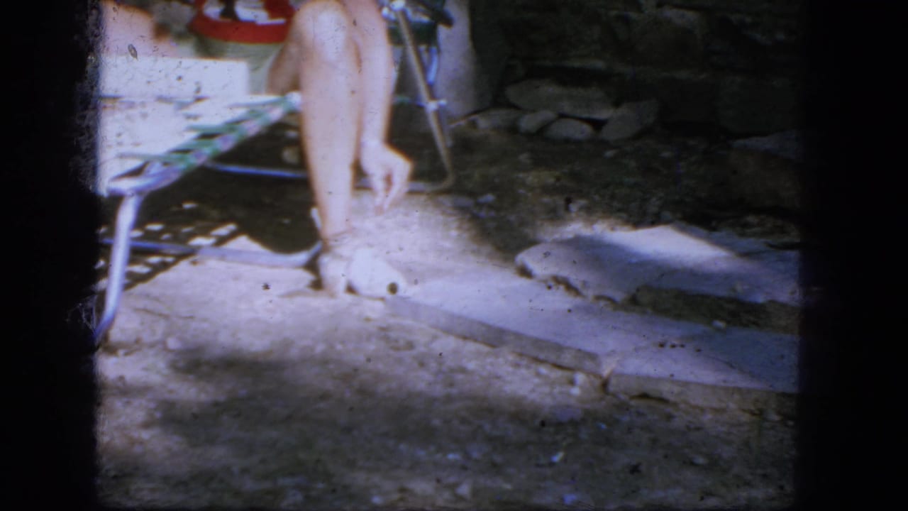 Person in a striped swimsuit seated on a lawn chair with a small animal near the ground.