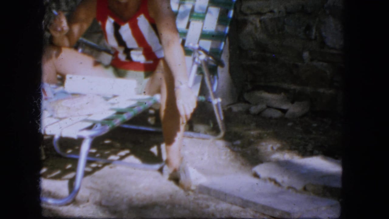 1964 Troy frame with a seated person in a striped swimsuit extending a hand toward a small chipmunk or squirrel in a backyard.