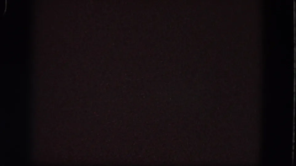 Underexposed 1964 Troy, New York 8mm frame with reddish-brown darkness, grain, and visible film edge.