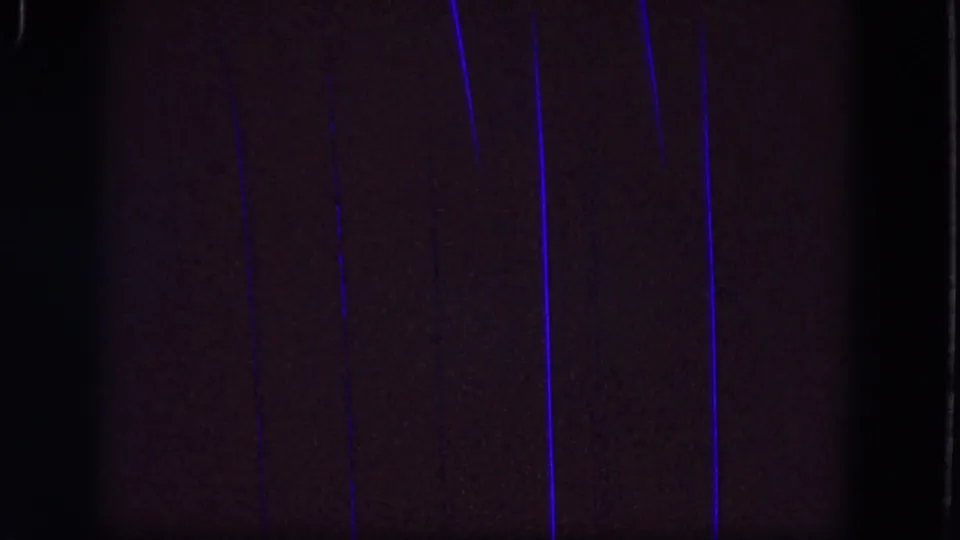 Dark 1964 Troy 8mm frame with several vertical blue light streaks, grain, and visible film gate edges.
