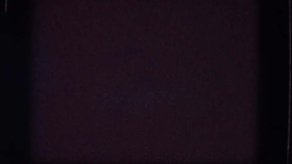 Dark 1964 8mm home-movie frame from Troy, New York with purple-brown grain, faint specks, and a visible film edge.