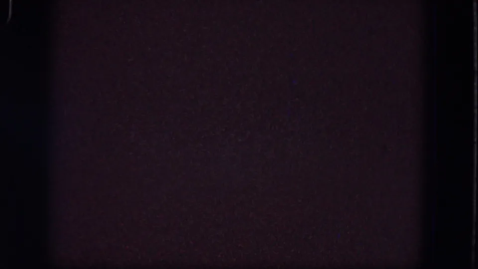 Dark 1964 8mm frame from the Troy reel showing dense grain, faint purple tones, and a vertical divider at the frame edge.
