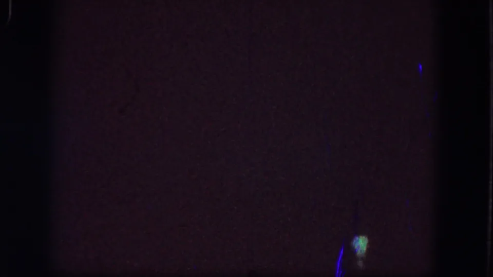 Dark 1964 8mm home-movie frame from Troy metadata showing blank exposure, film grain, edge shadow, and minor light specks.