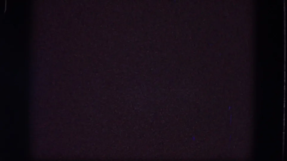 Nearly black 8mm frame from the 1964 Troy reel, with faint grain, edge marks, and minimal visible detail.