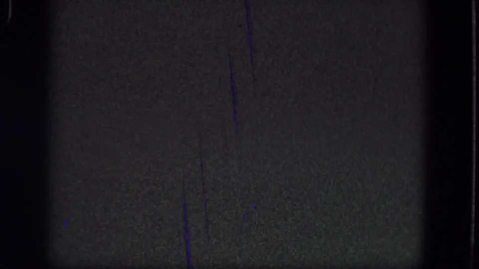 Gray-green 8mm frame from the 1964 Troy reel with vertical scratches, grain, dark edges, and low-contrast exposure.