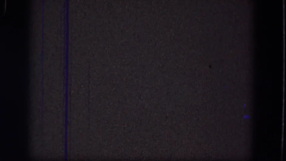 1964 8mm home-movie frame from Troy metadata showing mostly blank, dark grain with edge shadows and faint blue line artifacts.