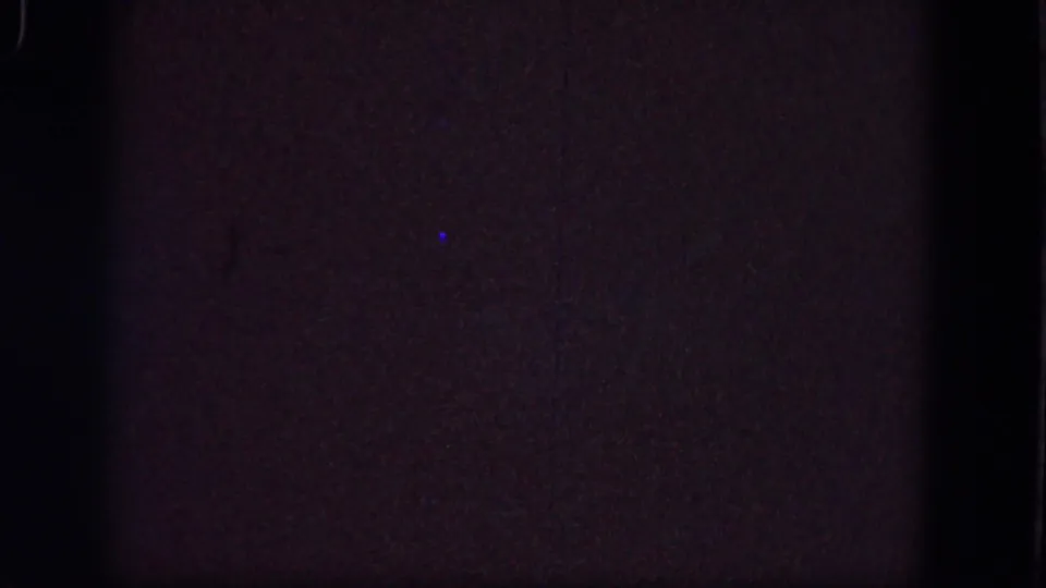Troy 1964 metadata frame showing a nearly blank 8mm film area with low exposure, grain, edge darkness, and blue speckling.