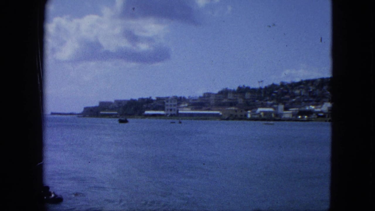 Wide water and shoreline view bordered by dark vertical frame edges, with boats and clouds in the distance.