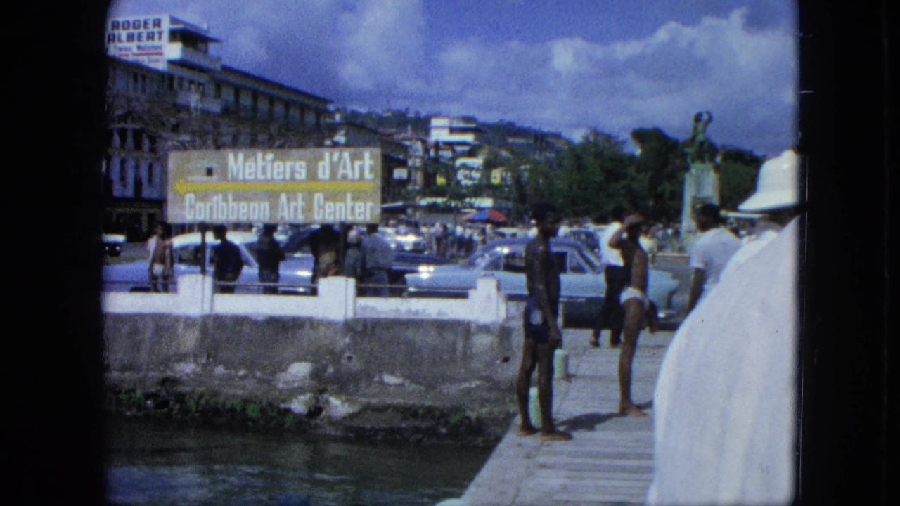 Men stand near a canal and art center sign with cars and buildings behind them.