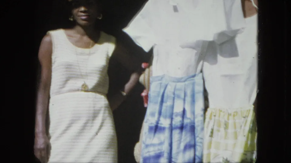 Final frame shows the woman at the edge of a shaded shopfront beside white shirts and patterned skirts in bright outdoor light.