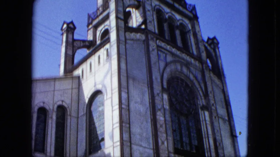 1964 U.S. Virgin Islands frame showing the building's upper section with large arched window, decorative roofline, and tower-like elements.