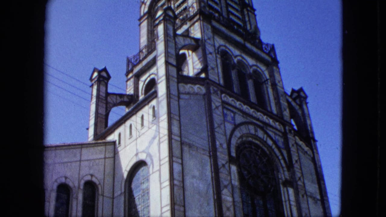 Low-angle view of an ornate church tower with arched windows against blue sky.