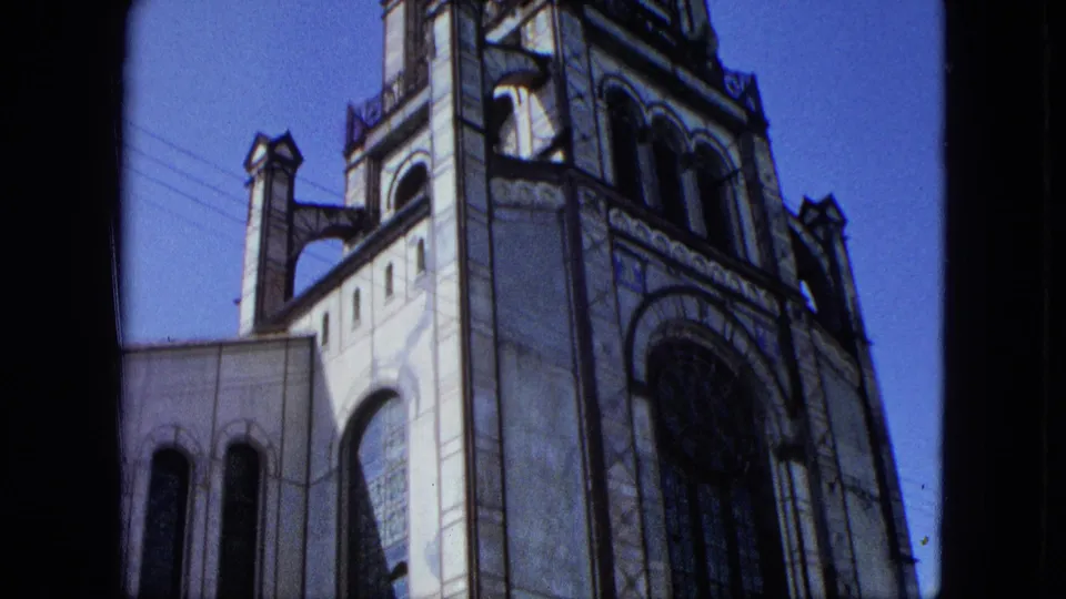 1964 U.S. Virgin Islands 8mm frame showing a stone church facade with tower details, arched windows, and part of a rose window.