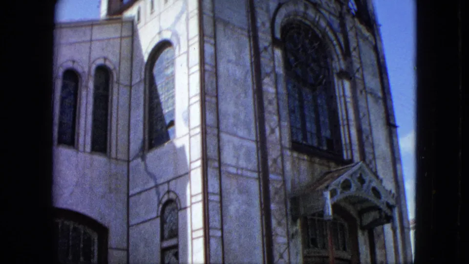 1964 U.S. Virgin Islands 8mm frame showing the church facade with rose window, tall stained-glass windows, and a small entrance canopy.