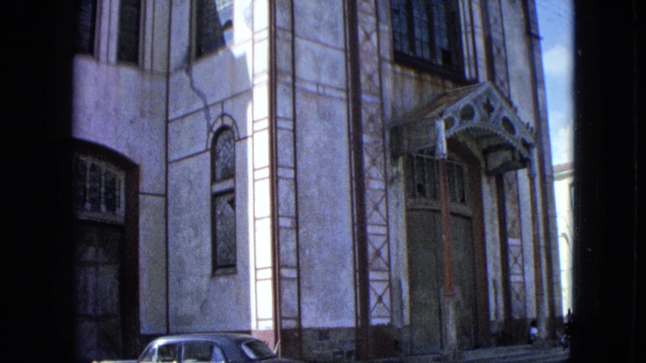 1964 U.S. Virgin Islands church exterior with entrance canopy, tall windows, and a parked mid-century sedan at the edge of frame.