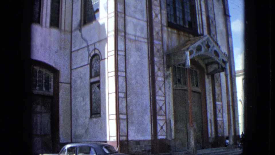 1964 U.S. Virgin Islands church exterior with entrance canopy, tall windows, and a parked mid-century sedan at the edge of frame.