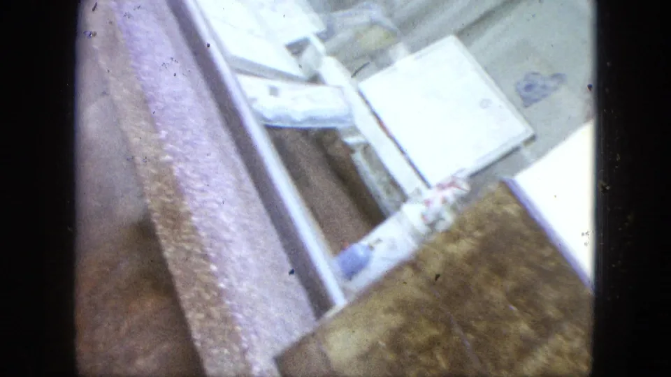 Tilted 1964 home-movie close-up of church entrance details, including steps, railing, and textured exterior wall surface.