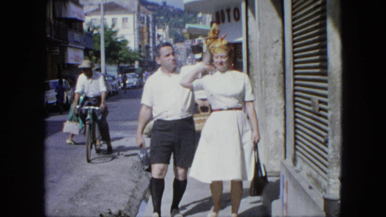 Man and woman walk beside a storefront as a cyclist and pedestrians move along the street.