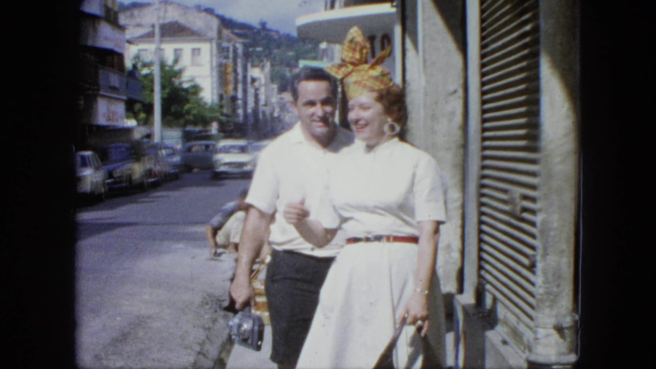 Man and woman walk toward the camera on a sunny city sidewalk.