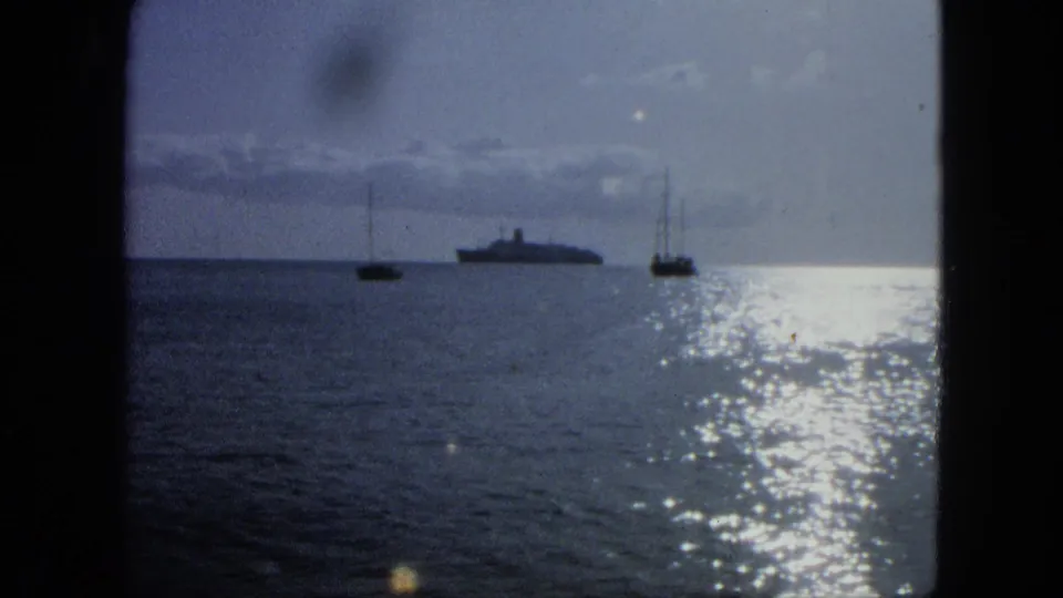 1964 USA Virgin Islands 8mm frame showing a large ship between small sailboats, with bright water glare and soft film color.