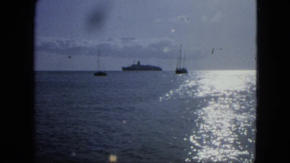 1964 USA Virgin Islands frame with two sailboats, a distant large ship, sunlit water, and visible 8mm film texture.