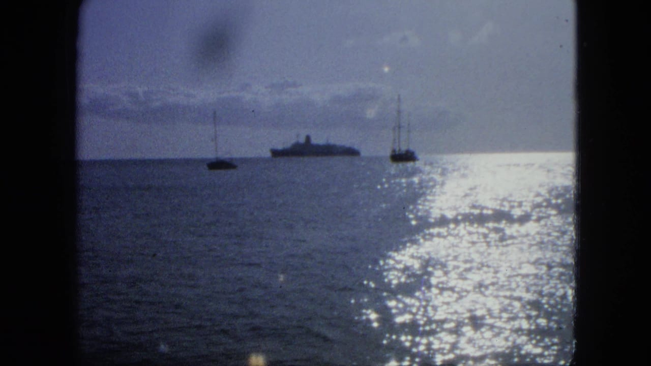 Distant ship and two small sailboats on a sunlit ocean horizon.