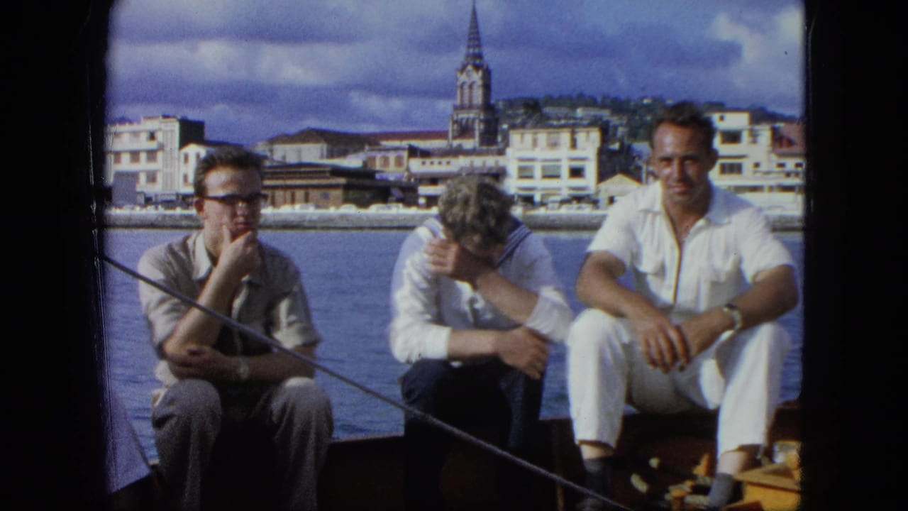 Three men sit on a boat, one resting his head, with a harbor town and steeple behind them.