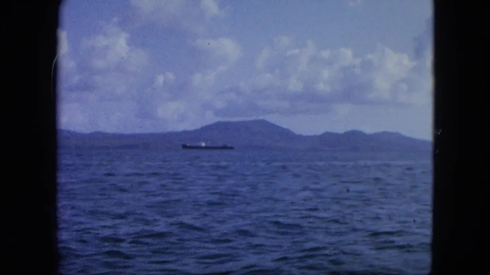 A boat passenger's view across water toward a distant ship and low island silhouettes in the USA Virgin Islands setting.