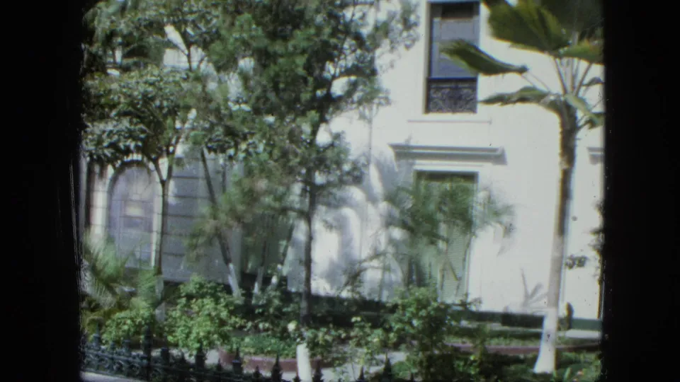 Final frame shows the landscaped facade with rectangular and arched windows, palms, shrubs, and visible 8mm contact-sheet borders.