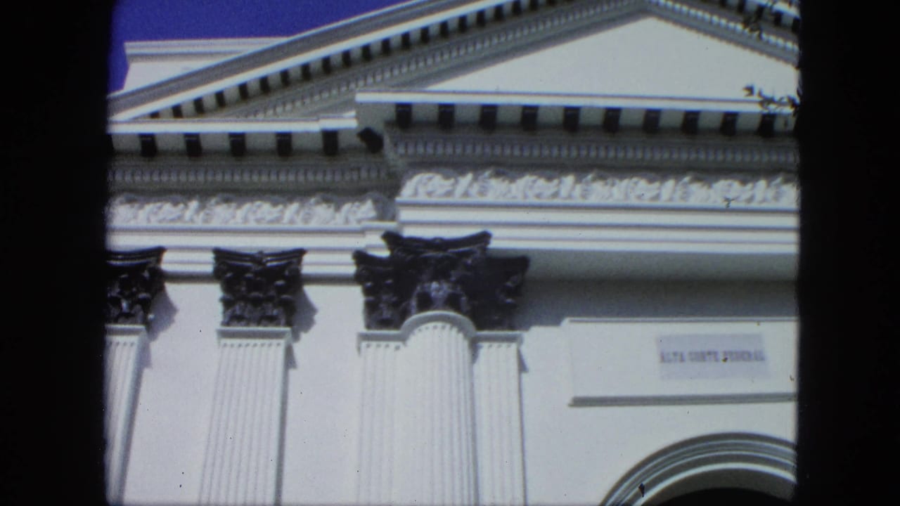 Upper facade with pediment, columns, cornice detail, and a small sign.