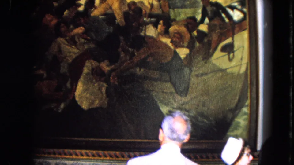 1964 Venezuela travel footage shows a visitor seen from behind viewing a large framed historical painting in an indoor setting.