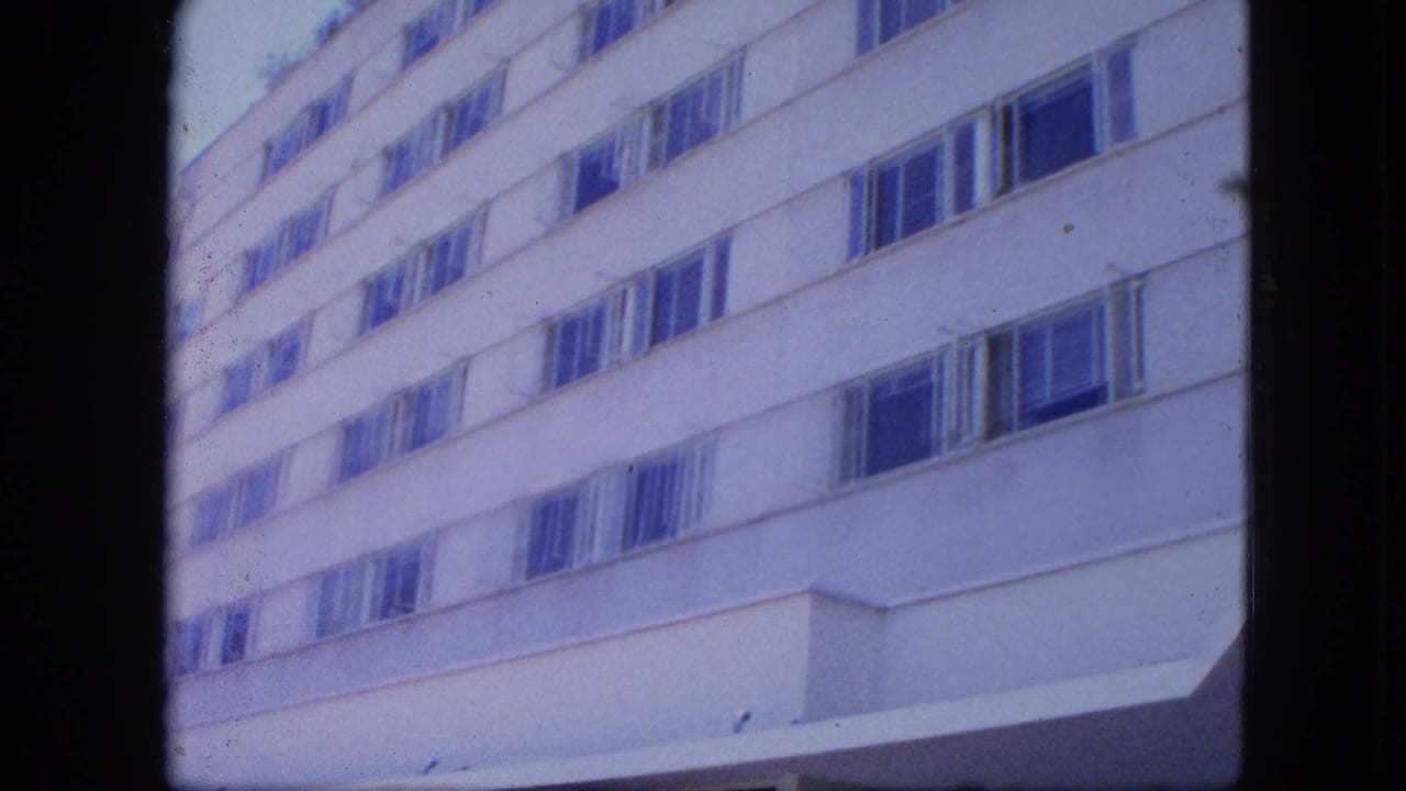 Low-angle view of a white high-rise facade with rows of windows.
