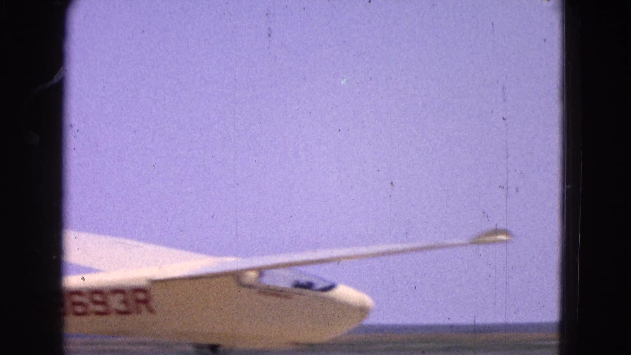 1964 8mm home-movie frame showing part of a glider with registration lettering at a Washington, DC area airfield.
