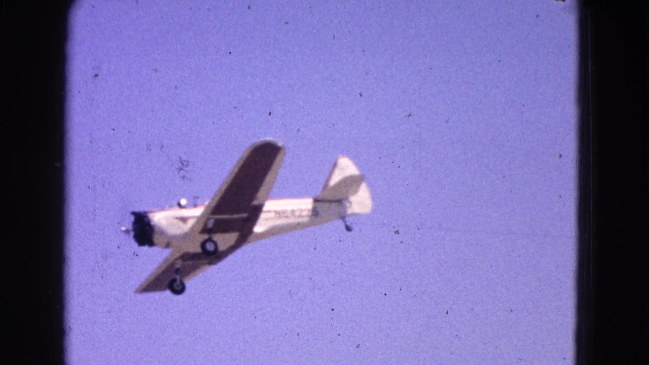 Small high-wing airplane flying across a pale blue sky.