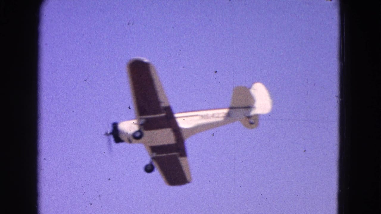 Small propeller airplane banked against a clear blue sky.