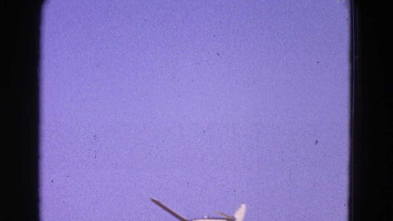 1964 Washington DC 8mm frame with a small white airplane partly visible near the lower edge against a purple-blue sky.