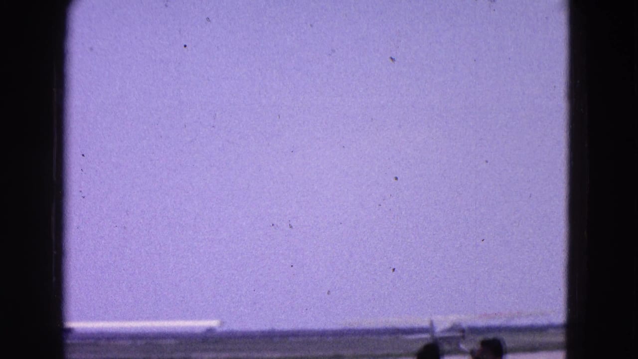 1964 Washington, DC runway view through a window, with a small plane near the edge and silhouetted spectators in front.