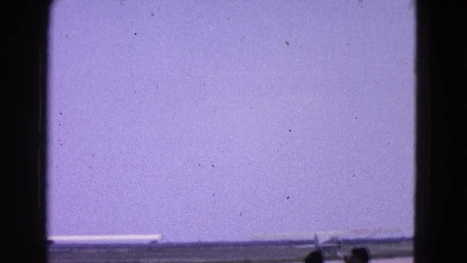 1964 Washington, DC runway view through a window, with a small plane near the edge and silhouetted spectators in front.