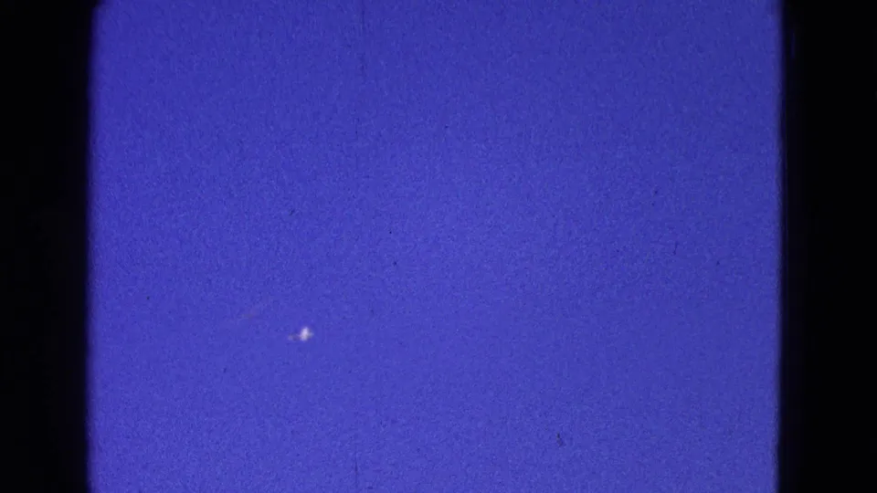 Final 1964 Washington, DC frame showing a distant bright aircraft mark in blue sky with visible 8mm film texture.