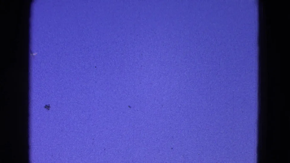 A mostly blue 8mm frame from the 1964 Washington DC clip, showing sky, grain, dust, and dark gate edges.