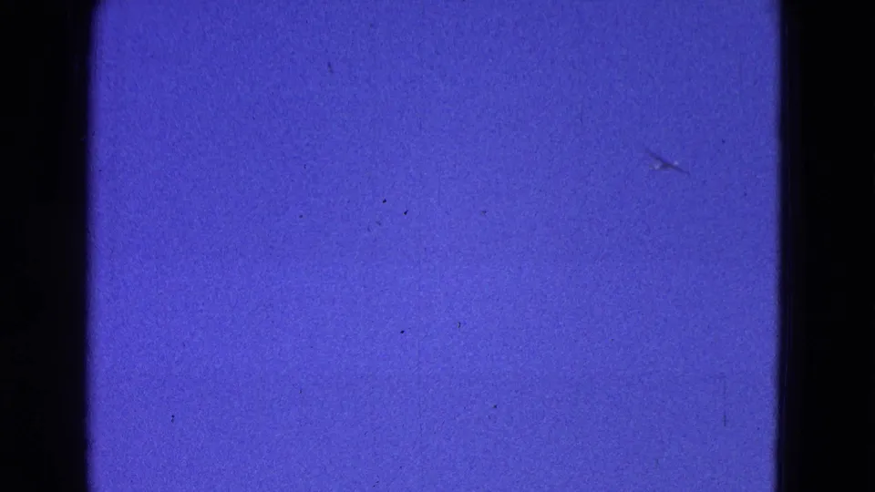 1964 Washington, DC 8mm home-movie frame with a faint bird shape against blue sky and visible film dust, grain, and edge shadows.