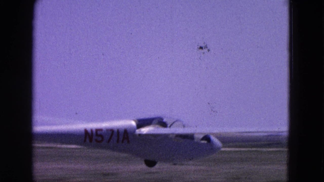 1964 8mm frame from Washington, DC area footage showing a glider marked N571A on an airfield runway.