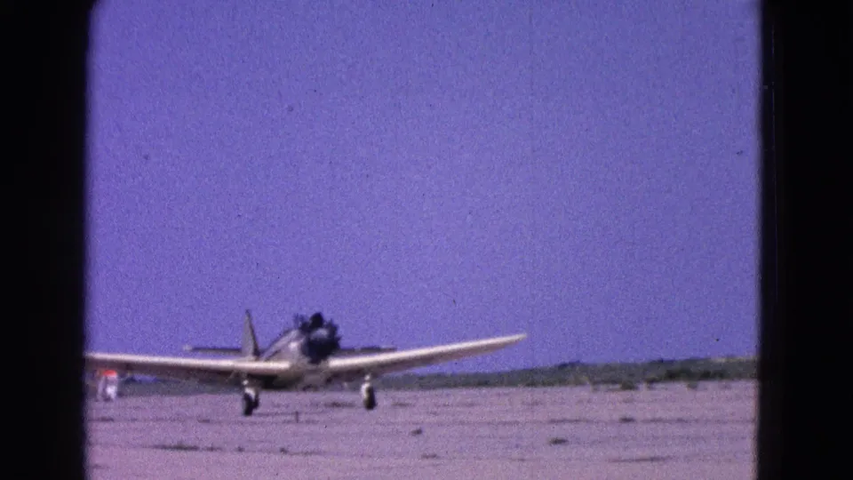 1964 8mm frame showing a small propeller aircraft on an airfield runway near Washington, DC.